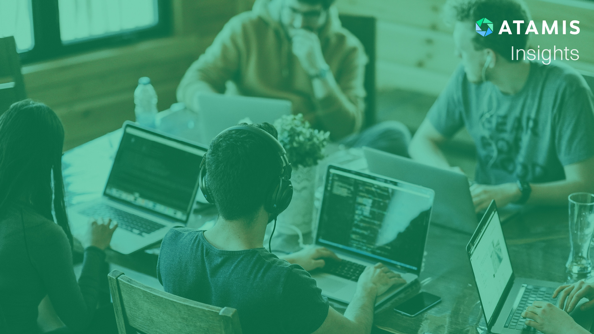 A group of people in an office all with laptops in front of them.